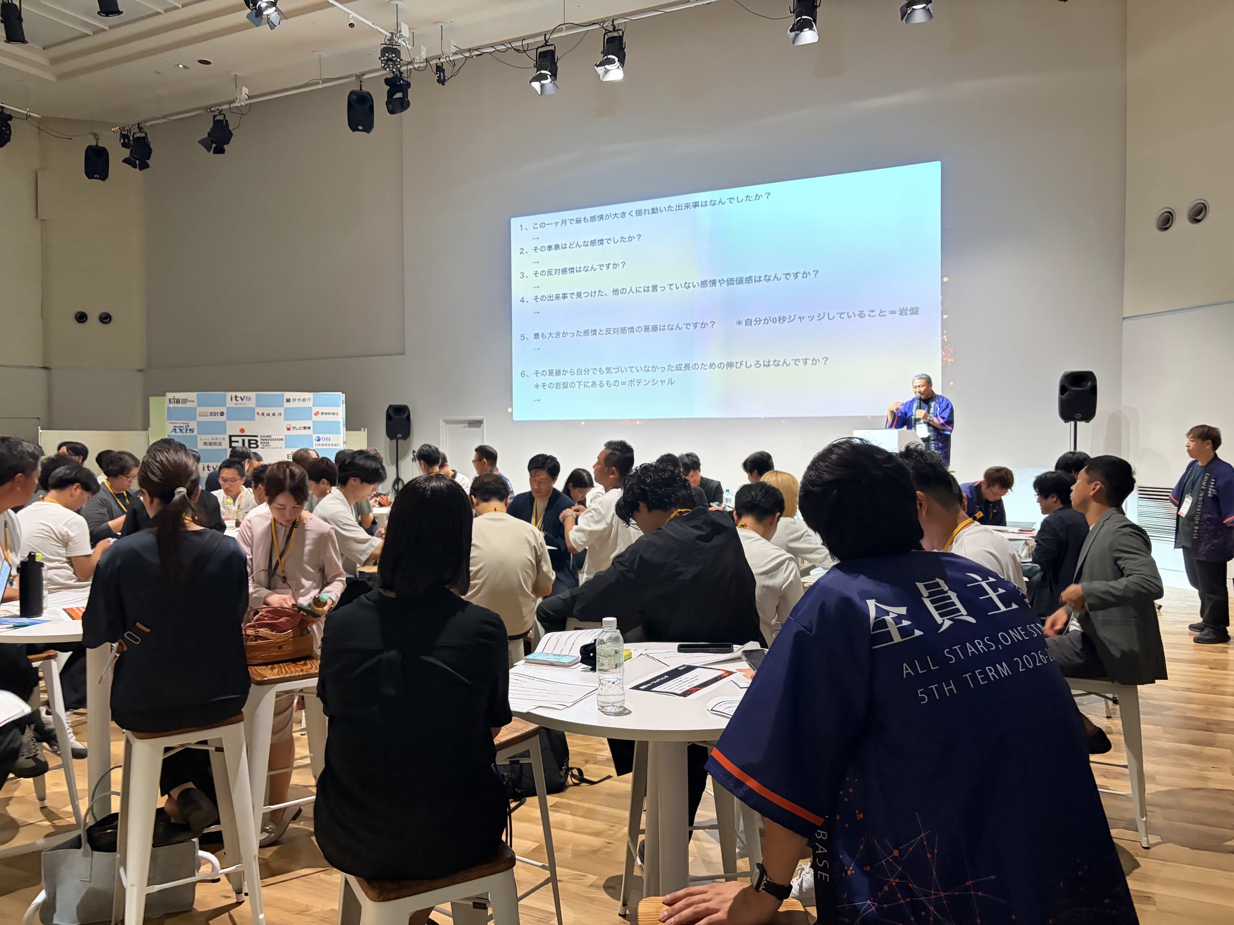 第5期キックオフ総会の会場。手前に「全員主役」の法被の背中