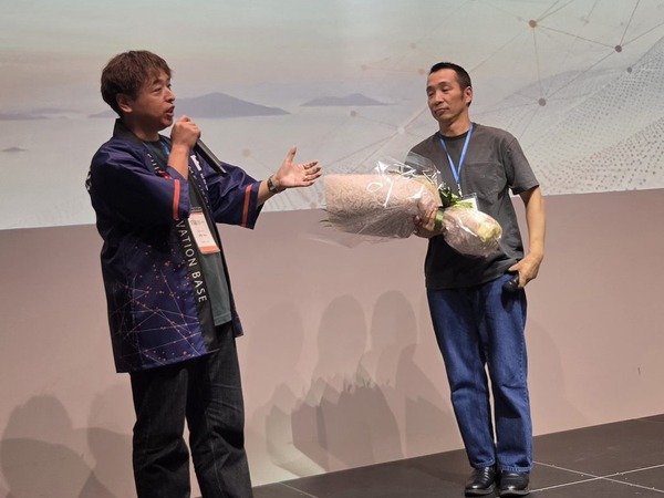 花束を手渡してバトンタッチする、前会長と第5期の代表