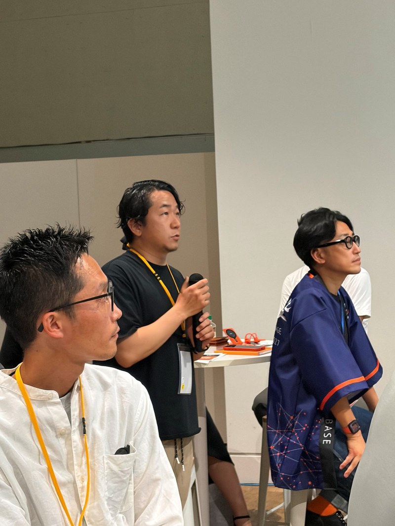 少人数の輪の中で、マイクを持って話す参加者と聞き手