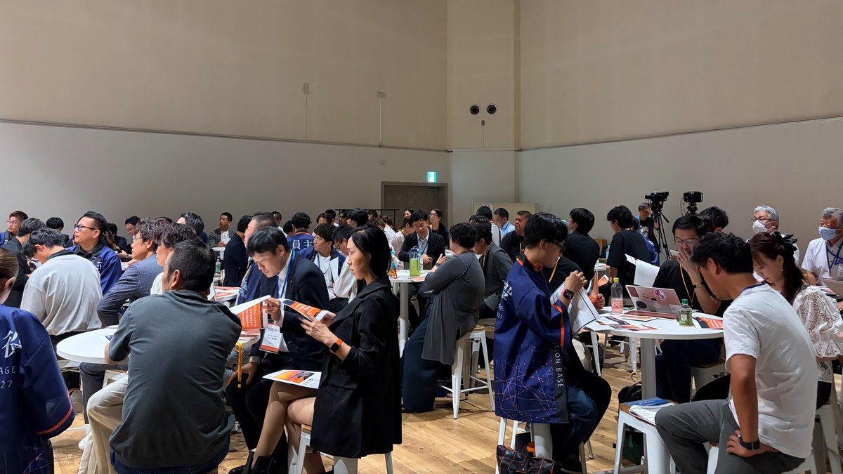 会場全体が小さなグループに分かれ、丸テーブルを囲んで向き合って話している様子