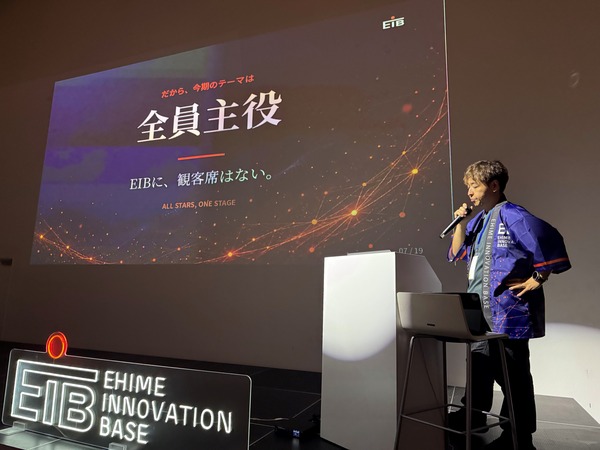 「全員主役 ／ EIBに、観客席はない。」と映し出されたスクリーンの前で、マイクを持って話す第5期会長