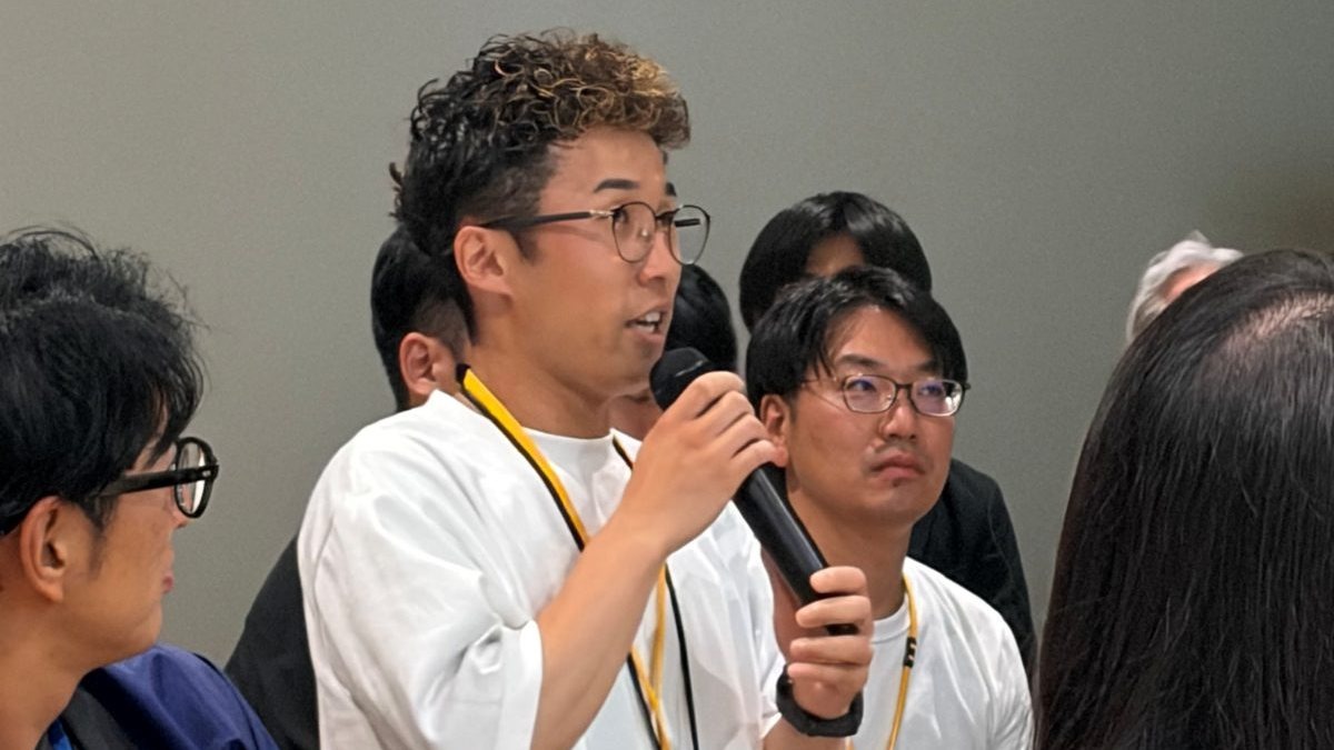 マイクを持って話す参加者と、それを聞く周囲の参加者